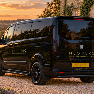 Black Neo Hero van with gold wordmark branding outside a country home at sunset.